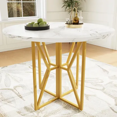 A round dining table with a marble-patterned top and gold geometric legs, placed on a rug in a room.