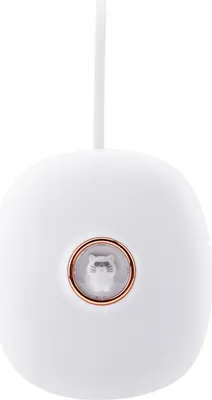 A white, pebble-shaped digital alarm clock with a rose gold ring around a small, clear window containing a white cat figurine.