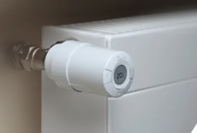 A close-up shot of a white radiator valve with a digital display showing '20°'.