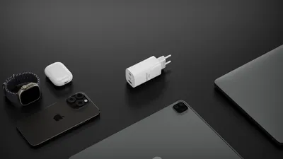 A collection of Apple electronic devices and a white charging adapter are arranged on a black surface.