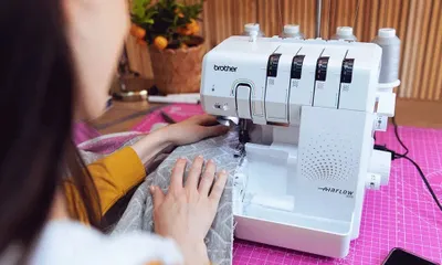 A person is using a Brother Airflow 3000 overlock machine to sew fabric.