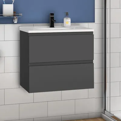 A gray bathroom vanity with two drawers is mounted on a tiled wall. A white sink is on top of the vanity, with a black faucet and a soap dispenser.