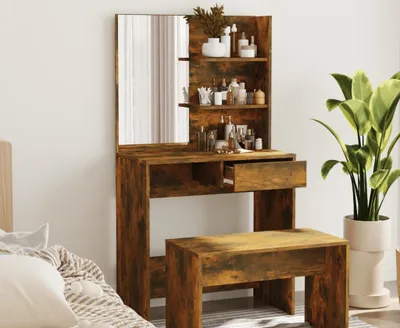 A vanity table with a mirror and a stool, set up in a room with a plant and a bed.