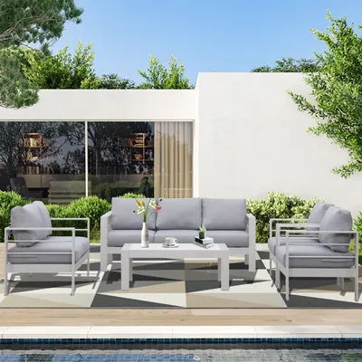 An outdoor patio setting with a modern grey sofa set and coffee table by a swimming pool.