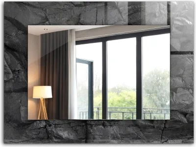 A mirror with a stone-like frame reflecting a room with a lamp and a large window overlooking trees.