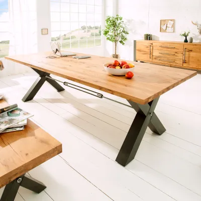 A spacious dining room with a large wooden dining table and a sideboard in the background.