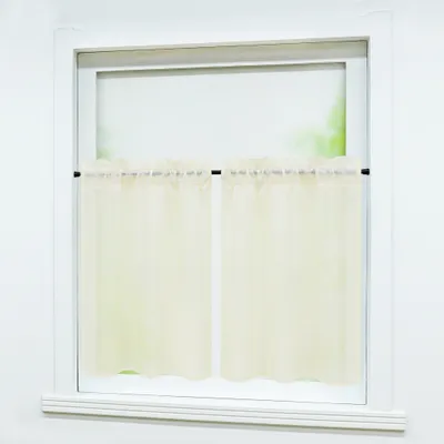 A close-up view of a window with sheer beige curtains.