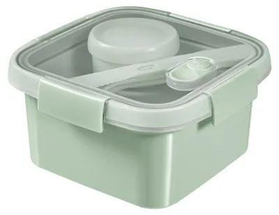 A square green lunchbox with a transparent lid and a small container inside, along with cutlery.