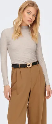 A woman modeling a beige long-sleeved shirt and brown pants.