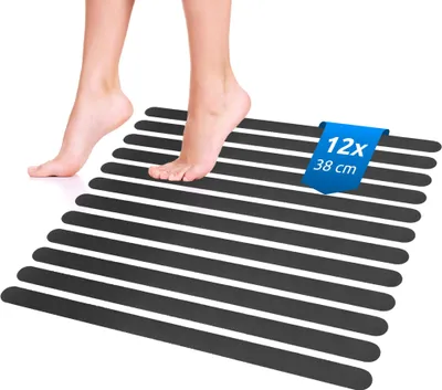 A person's feet stepping onto a set of black anti-slip strips arranged in parallel on a white surface.