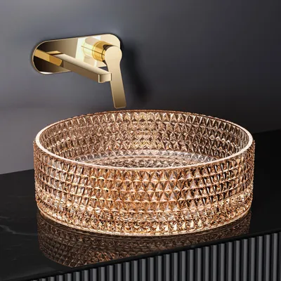 A close-up shot of a decorative glass sink and a gold faucet mounted on a dark wall.