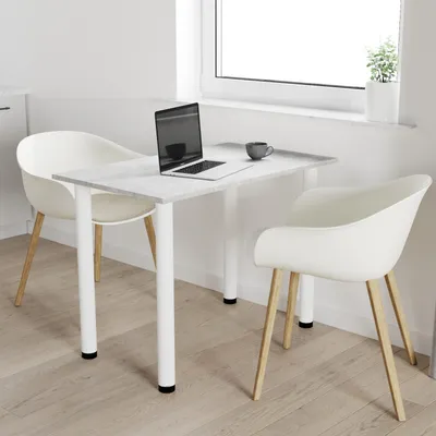 A small dining table with two chairs, a laptop, and a coffee cup, set up in a bright room near a window.
