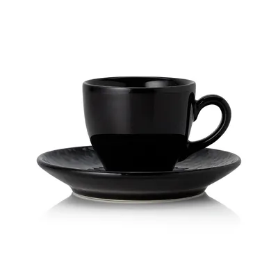 A black ceramic cup and saucer photographed on a white background.