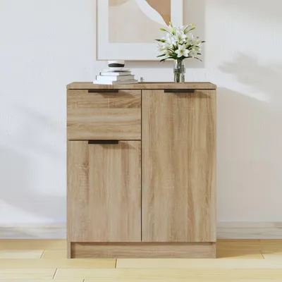 A wooden sideboard with two drawers and two doors, placed against a white wall with a framed picture and a vase of flowers on top.