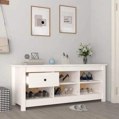 A white wooden shoe cabinet with various shoes and decorative items on top, placed in a hallway.