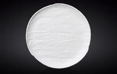 A white, textured plate on a dark, reflective surface.