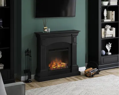 A black electric fireplace with a realistic flame effect is shown in a living room setting, with a bookshelf and a TV in the background.