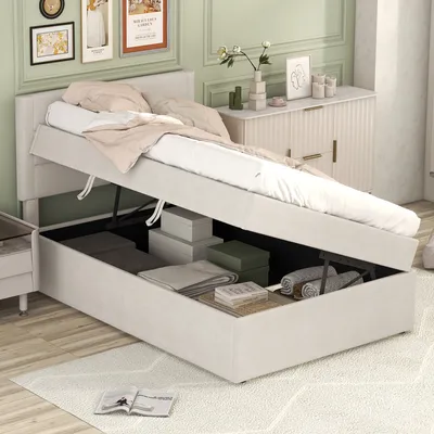 A bedroom scene with a bed that has its storage compartment open, revealing stored items.