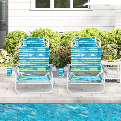 Two beach chairs are set up on a patio next to a swimming pool.
