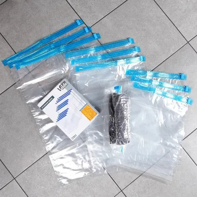 A collection of vacuum seal bags and a box of storage bags laid out on a tiled floor.