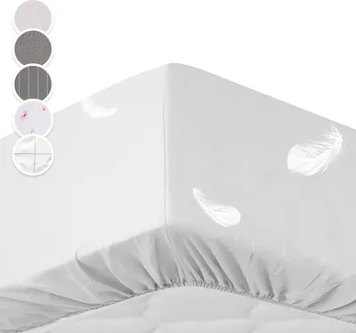 A white fitted sheet with a subtle feather pattern is shown on a mattress, with a corner folded over.