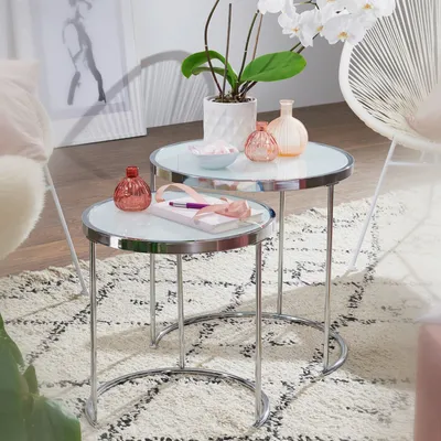 A set of nesting tables with decorative items on them, placed on a rug in a living room setting.