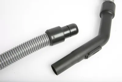 A close-up shot of a vacuum cleaner hose and a bent pipe attachment, isolated on a white background.