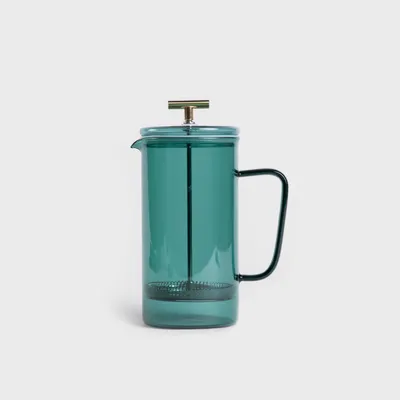 A green glass French press coffee and tea maker with a gold handle on a white background.