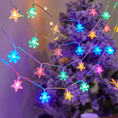 A string of colorful LED lights shaped like stars and snowflakes is draped over a decorated Christmas tree.