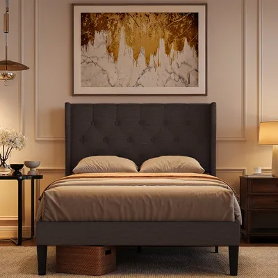 A bedroom scene featuring a bed, artwork, and a nightstand.