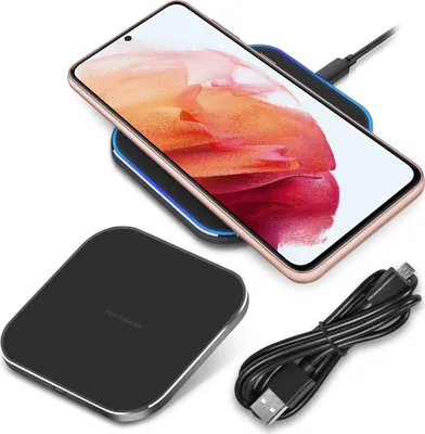 A smartphone is wirelessly charging on a charging pad, with a charging cable nearby.
