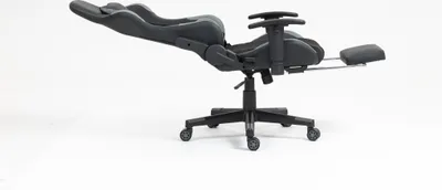A black and gray gaming chair with a footrest extended, shown from the side against a white background.