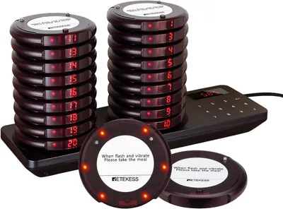 A set of restaurant pagers and their charging base.