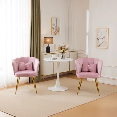A living room scene with two pink velvet chairs and a small white table.
