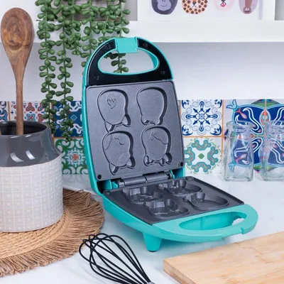 An open waffle maker with animal-shaped molds on a kitchen counter.