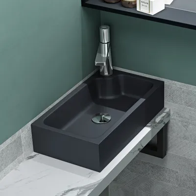 A modern bathroom sink with a faucet, set against a teal wall and marble countertop.
