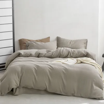 A neatly made bed with beige bedding and pillows, placed against a white wall.