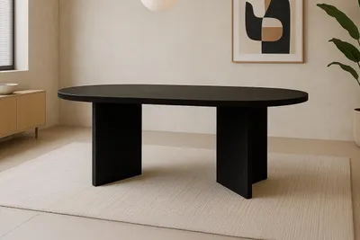 A modern dining room with a black oval dining table as the centerpiece, placed on a light-colored rug. The room features a minimalist sideboard, a framed abstract artwork on the wall, and a large plant.