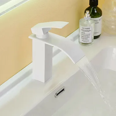 A white waterfall faucet in a bathroom sink with water flowing.