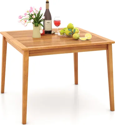 A wooden table with a bottle of wine, a glass of wine, flowers, and fruit.