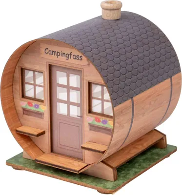 Raeucherfigur aus Holz in Form eines kleinen Fasses mit angedeuteten Fenstern und Tür darüber steht Campingfass steht auf einer kleinen grünen Holzplatte
