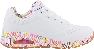 A white sneaker with a colorful heart pattern on the sole and lining.