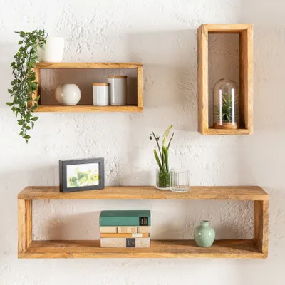 Three wooden shelves mounted on a white textured wall, decorated with various home decor items.