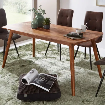 A dining table set in a room with chairs and a rug.