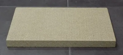 A rectangular beige object, likely a firebrick or insulation panel, is placed on a dark gray tiled surface.