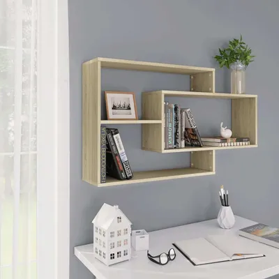 A light oak wood floating shelf unit is mounted on a gray wall above a white desk.
