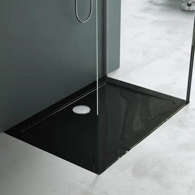 A modern black shower tray with a chrome drain in a bathroom setting.