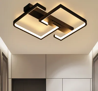 A modern black geometric ceiling light fixture with integrated LED lighting is shown mounted on a white ceiling.