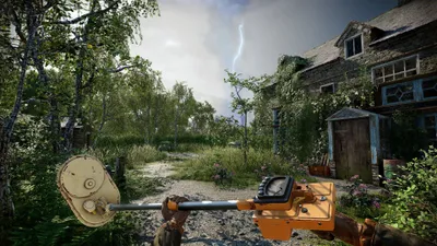 A first-person perspective of someone holding a metal detector in a rural, overgrown setting with an abandoned house in the background.