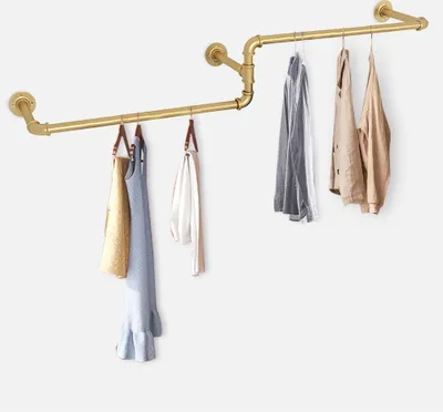 A gold-colored pipe clothing rack with several garments hanging on it, against a white background.